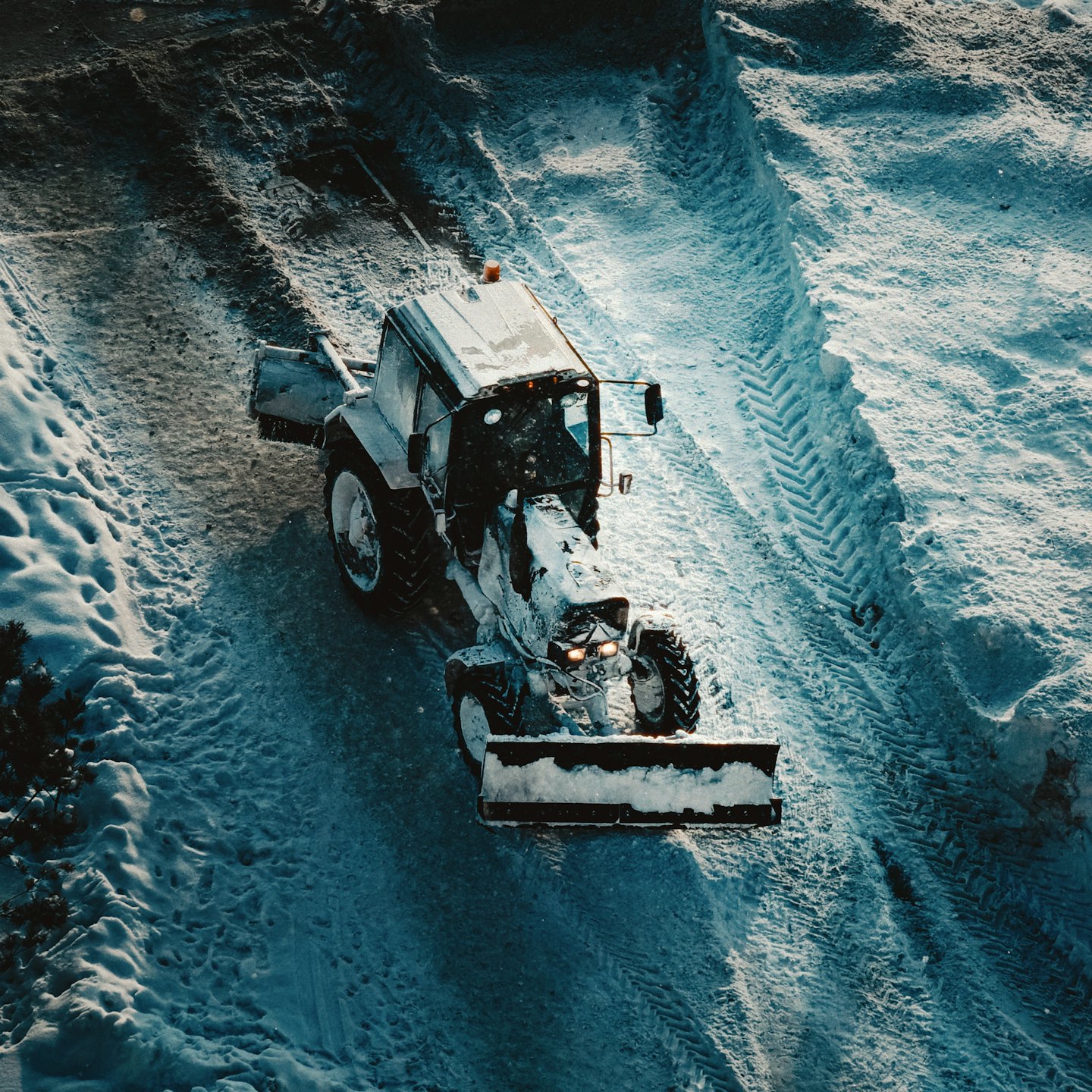 A snow plow clears a path through deep winter snow.
