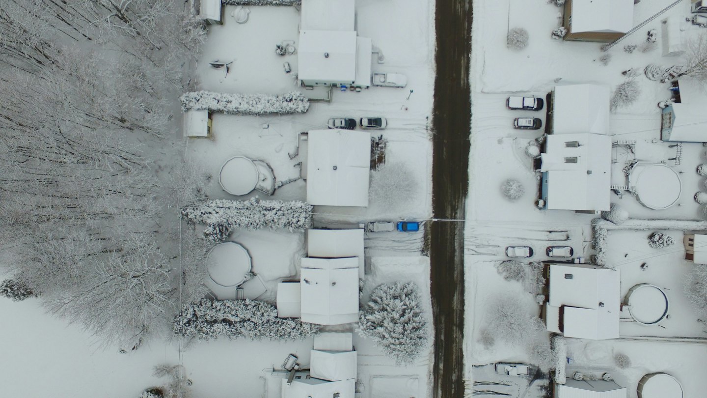 Snow covered houses line a quiet suburban street during winter.